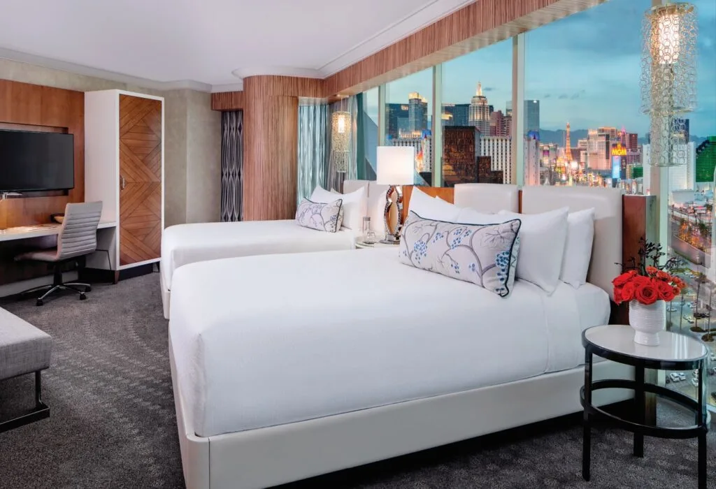 Two queen beds in the suite, up against a window with a view of the Strip. 