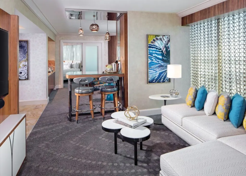 A bright living area with a white sectional couch pointed at a wall mounted TV. 