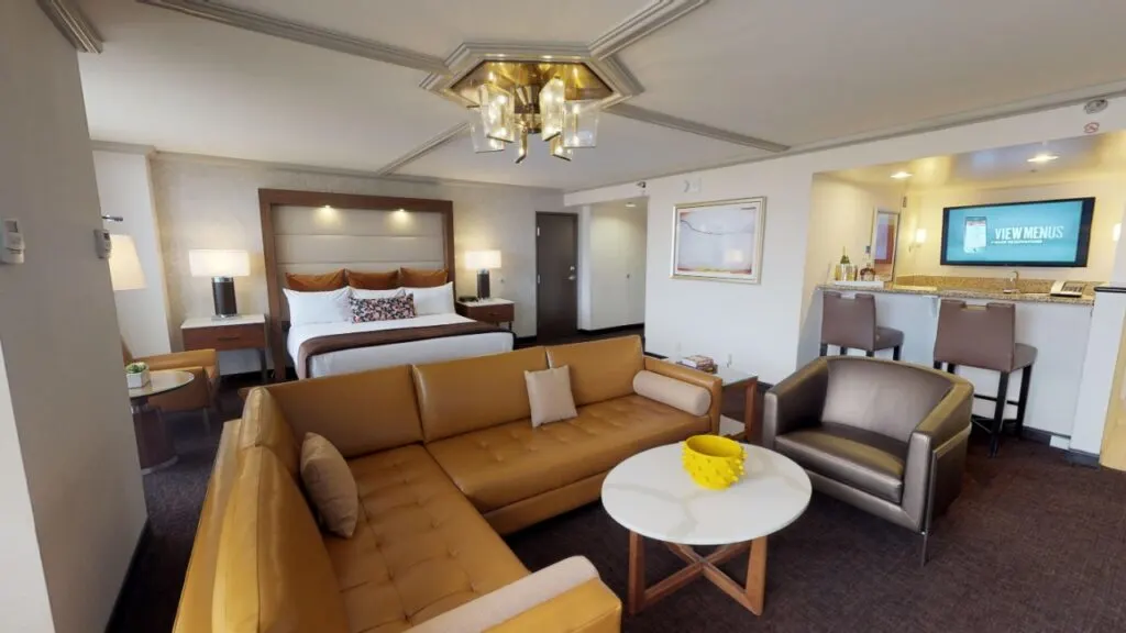 Suite at Palace Station with a sectional couch in the foreground and king bed in the background