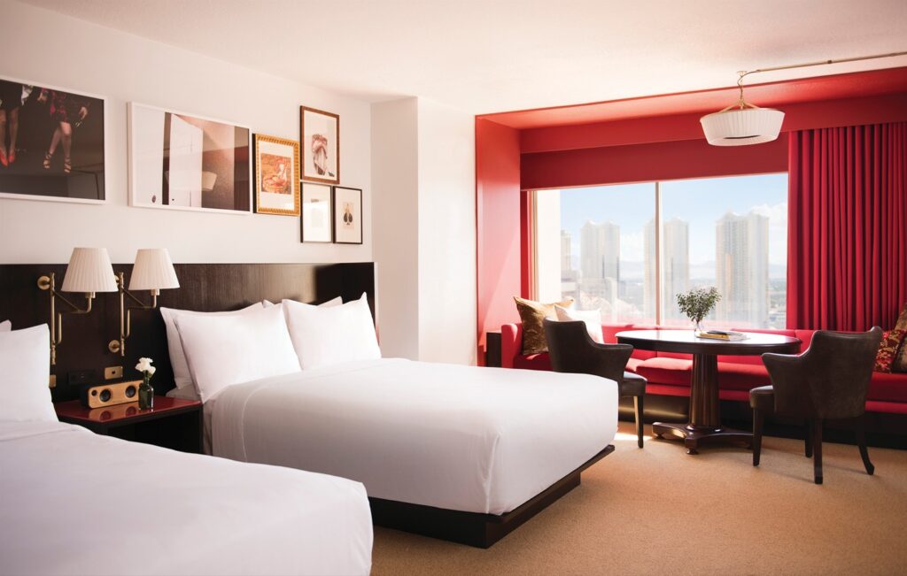 A suite with 2 queen beds, a red accent wall, and trendy wall decor.
