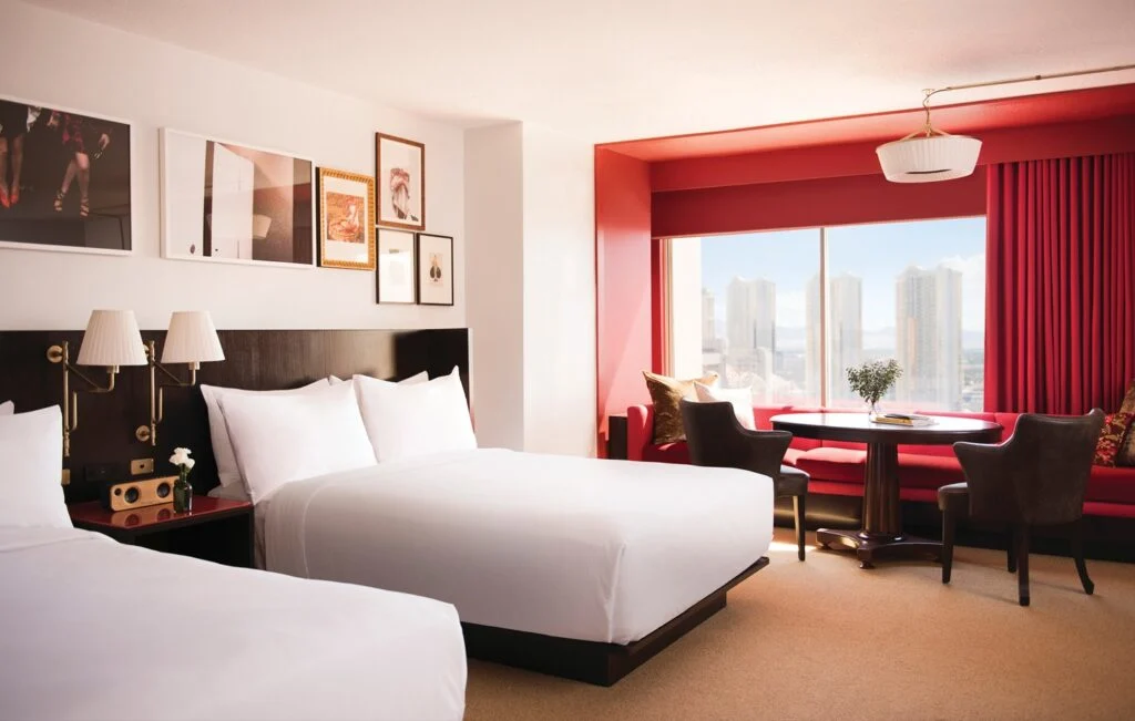 A suite with 2 queen beds, a red accent wall, and trendy wall decor.