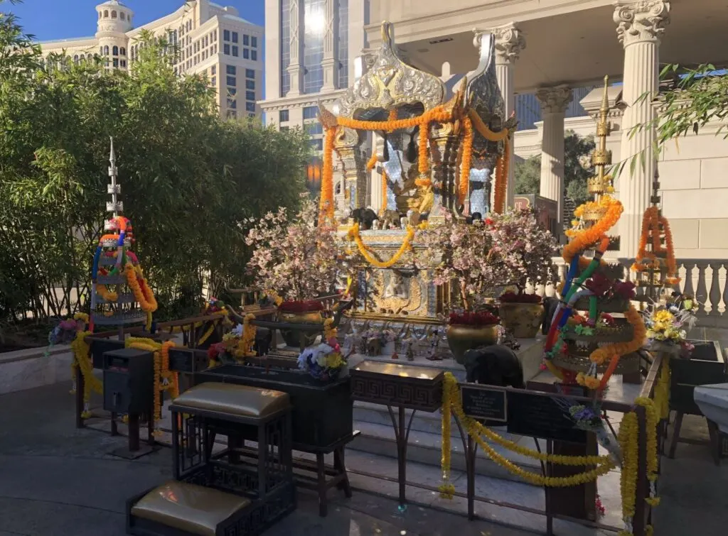 An outdoor shrine at Caesars Palace with colorful plastic strands draped over statues. 