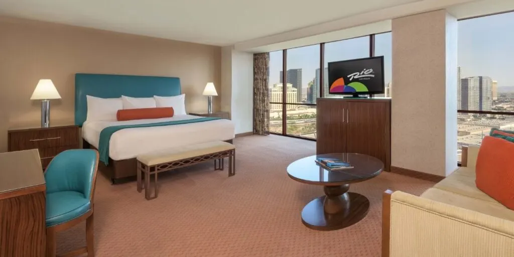 A suite at Rio overlooking the Strip with a king bed, couch, workdesk and coffee table.