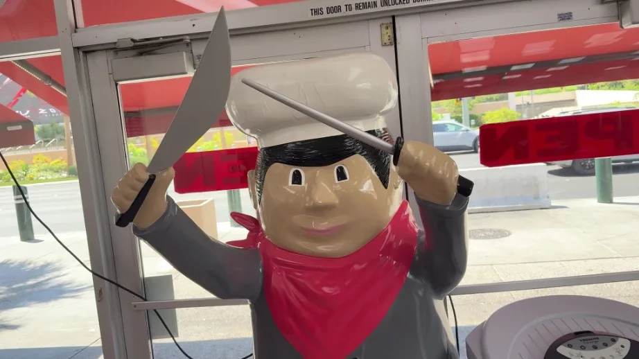 A statue emulating a worker, holding up two knives. 