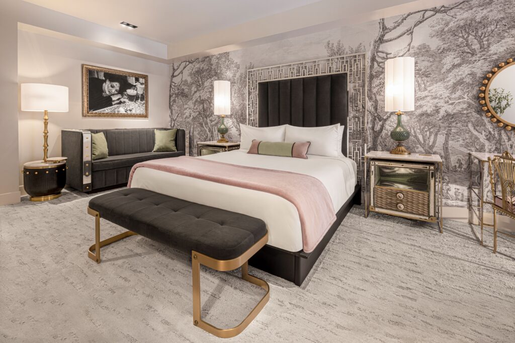 The bed in the new Vanderpump Hotel room with a bench at the end. It's pressed against a busy gray accent wall. 