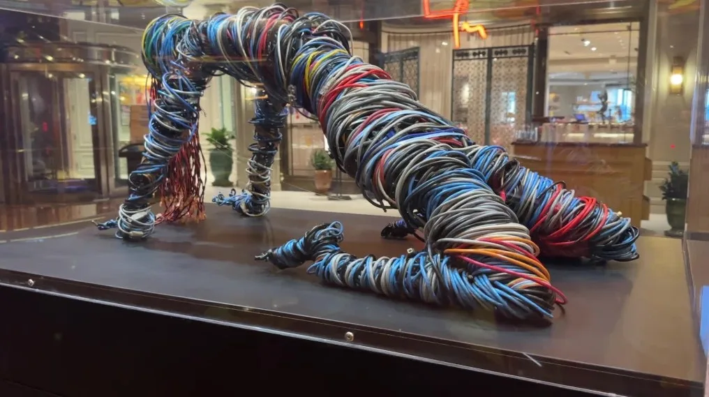 A woman made of wire in a glass case.