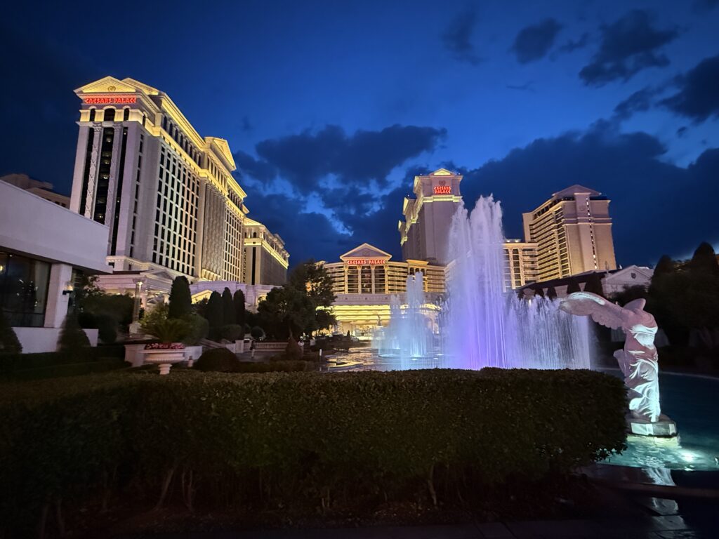 Exterior of Caesars Palace Las Vegas at night with fountains in the foreground.