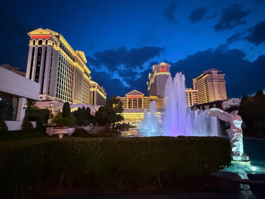 Exterior of Caesars Palace Las Vegas at night with fountains in the foreground.