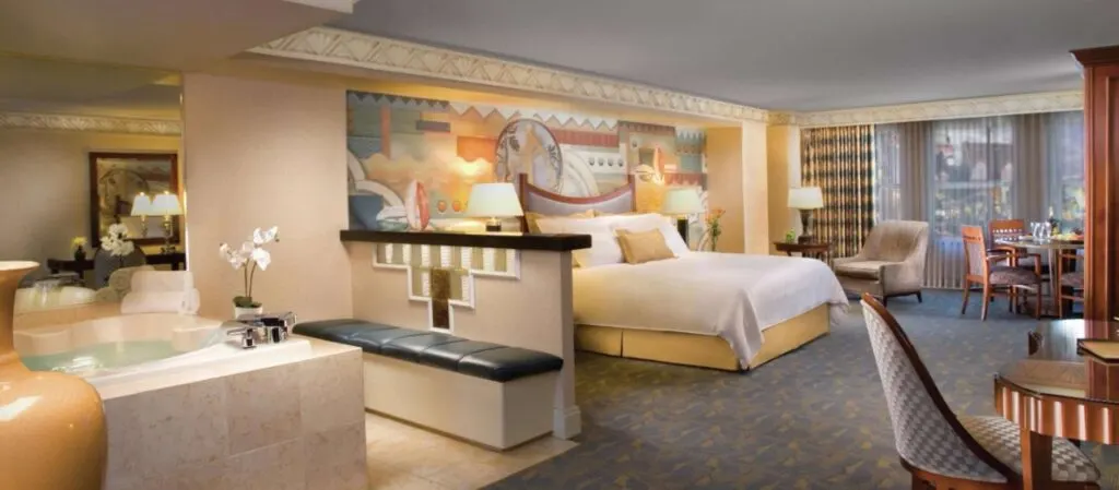 NYNY's Marquis Suite with a big bathtub in the foreground and a king bed in the background