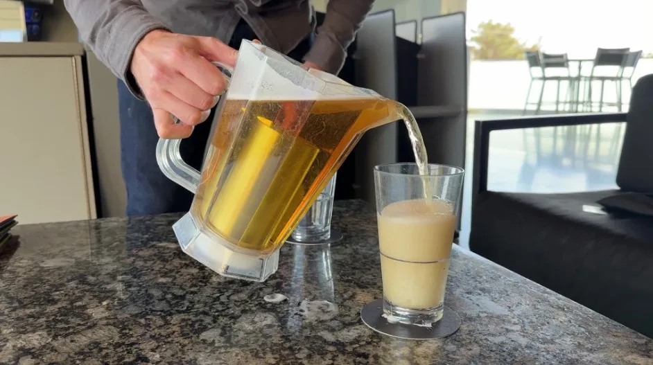A beer glass being filled from a pitcher. 