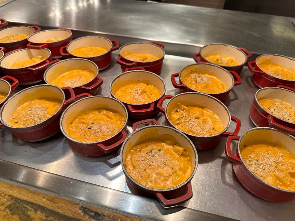 Little red individual pots of mac & cheese which have a cracker like dust sprinkled atop each.