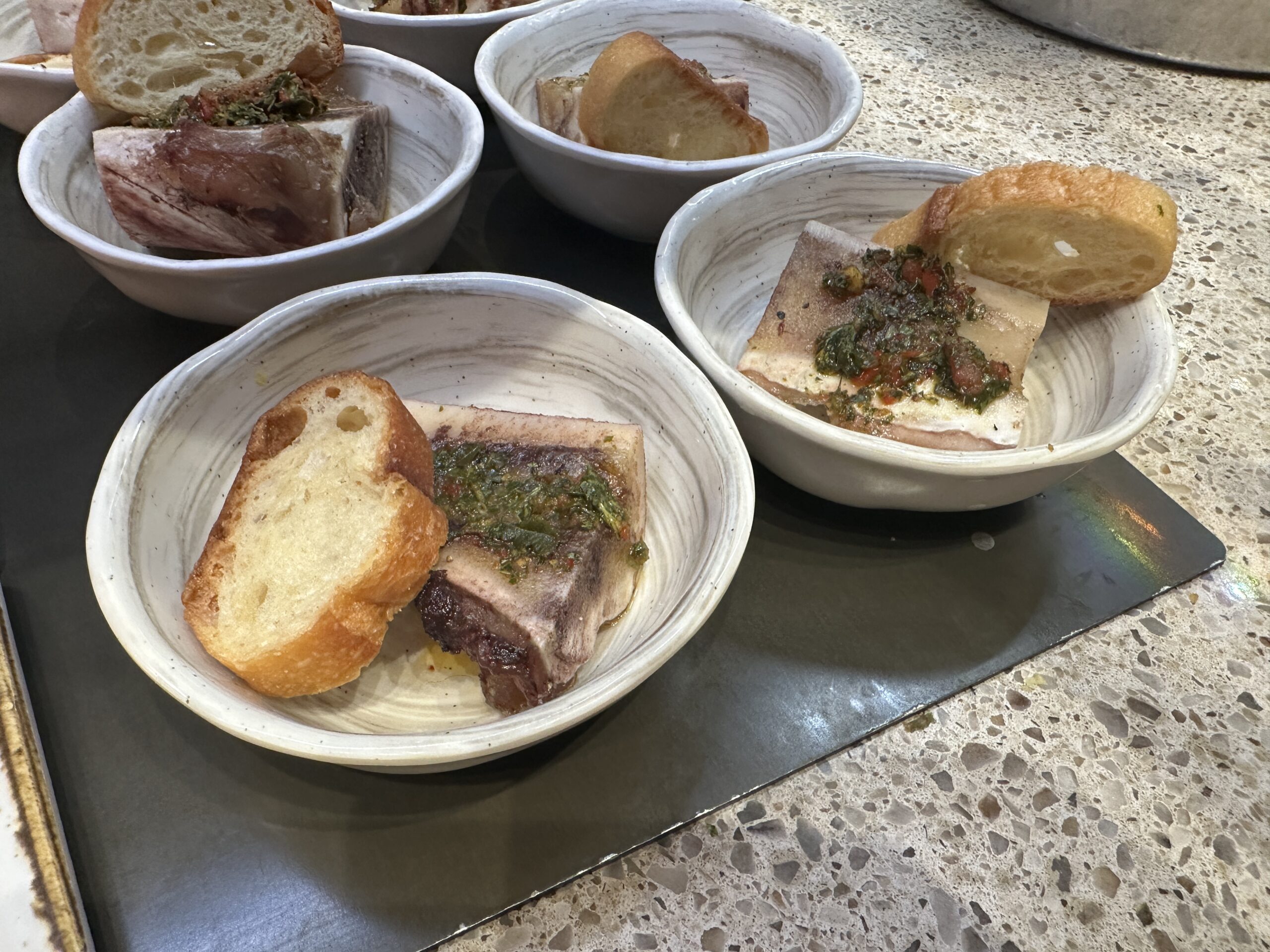 Individual servings of bone marrow, each served with a crusty piece of bread as well.