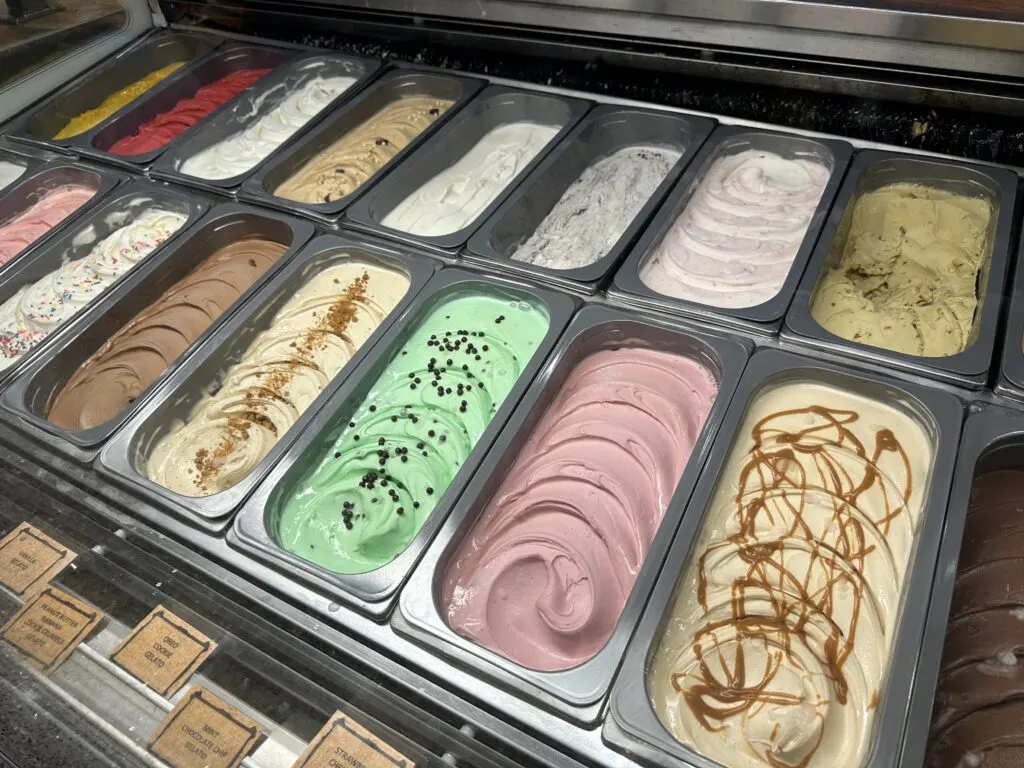 Tubs of colorful gelato under glass. 