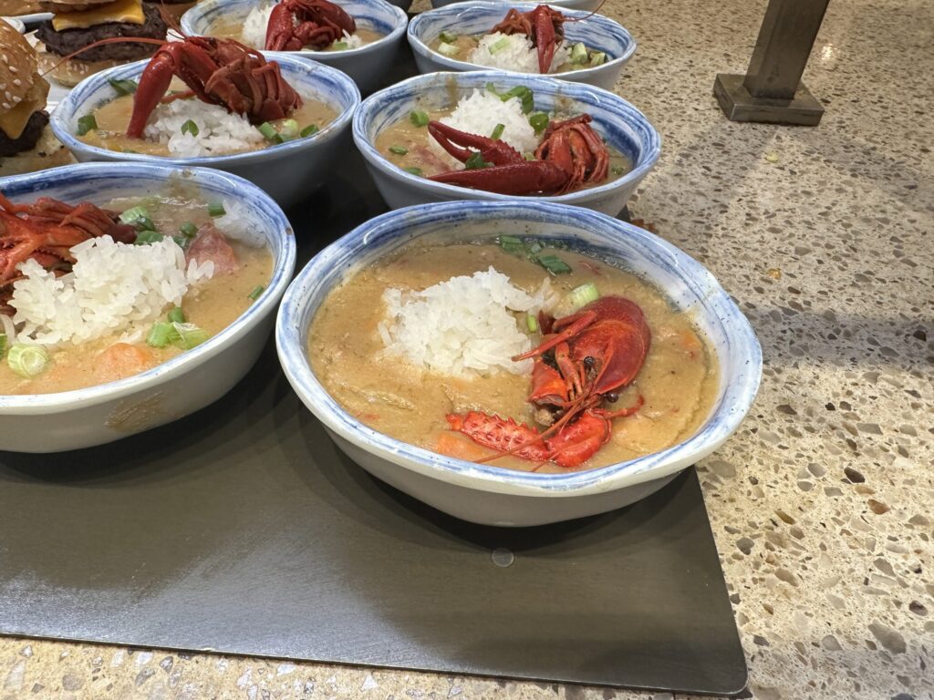 Individual serving of gumbo, which has a pile of rice and a crawfish visible.