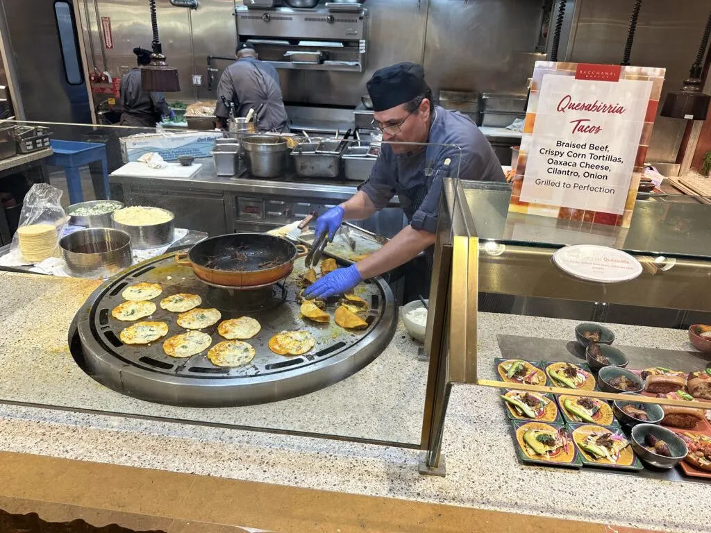 A chef folds tacos on a large griddle behind the counter at Bacchanal.