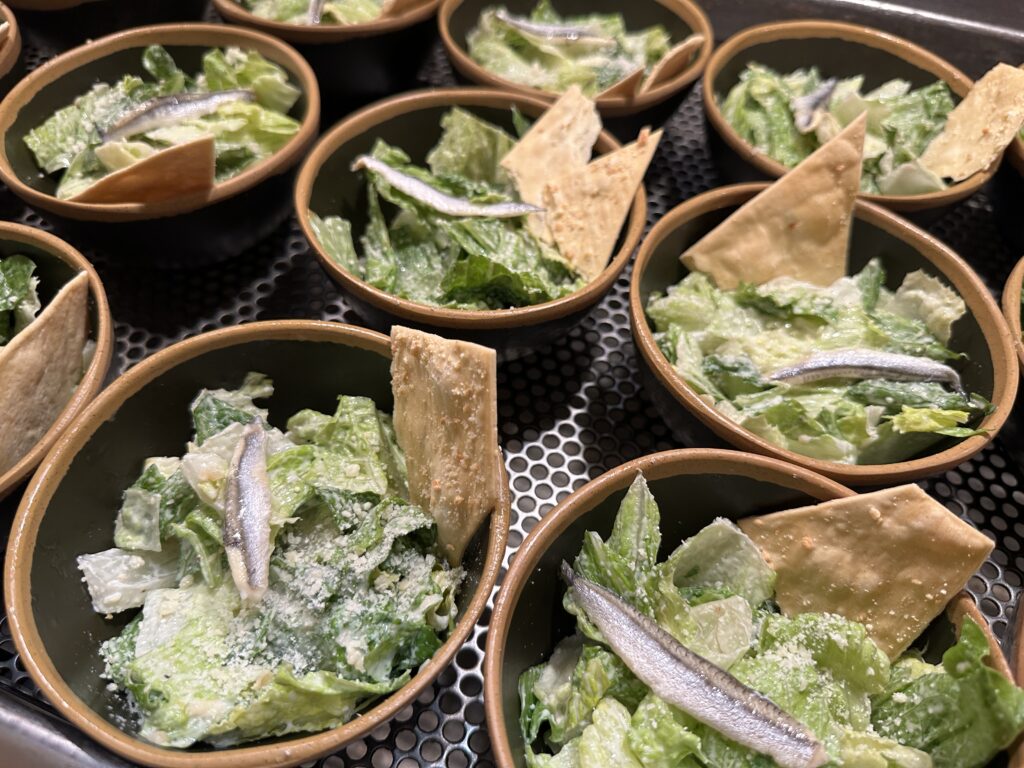 Salads in individual bowls with a chip sticking out of each. 