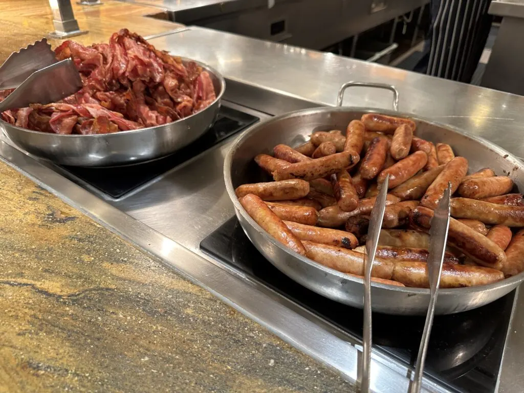 Bowls of bacon and sausage sitting side by side. 