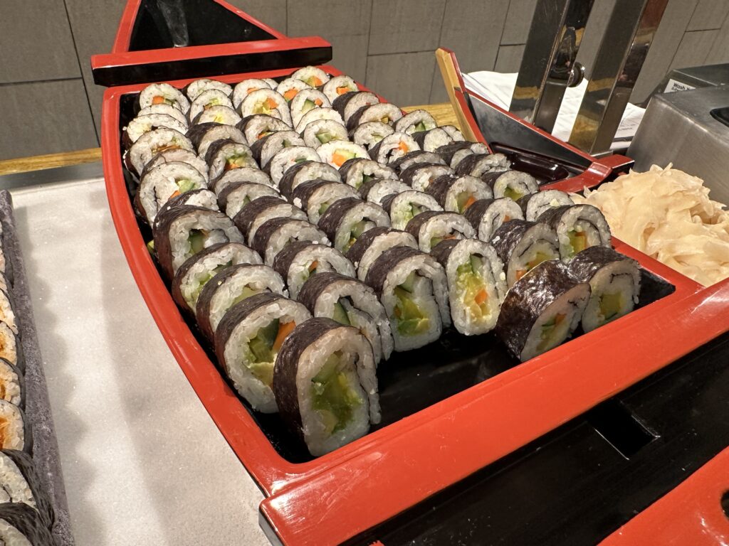 A decorative boat themed tray full of sushi. 