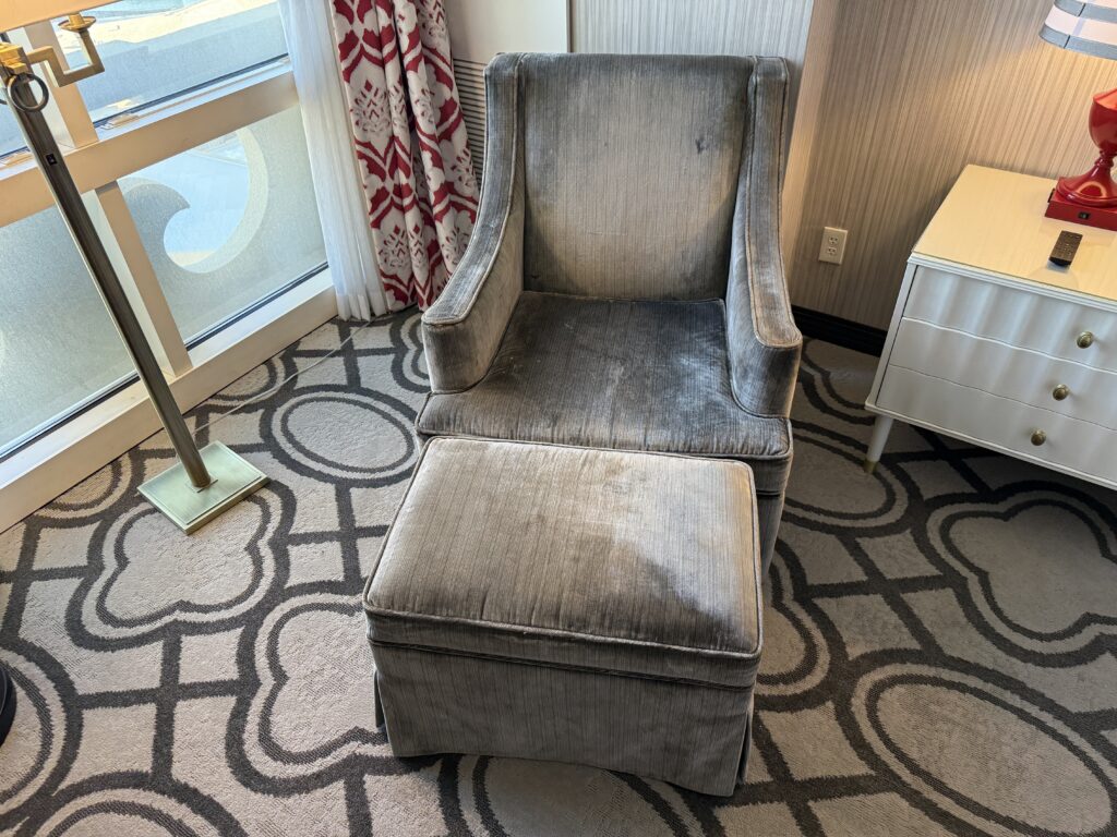 A chair with it's own ottoman in front of it sitting in the corner of the room in front of a window. 
