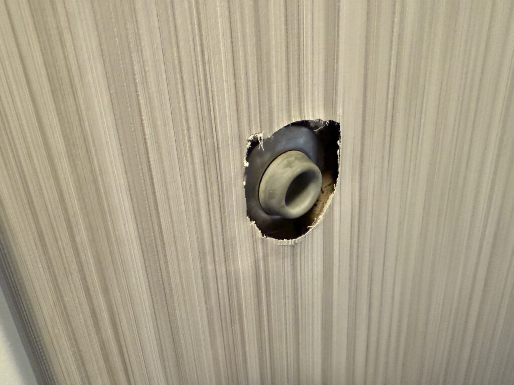 A door stop that has been pushed into the wall it was mounted on, leaving a hole in the wall. 