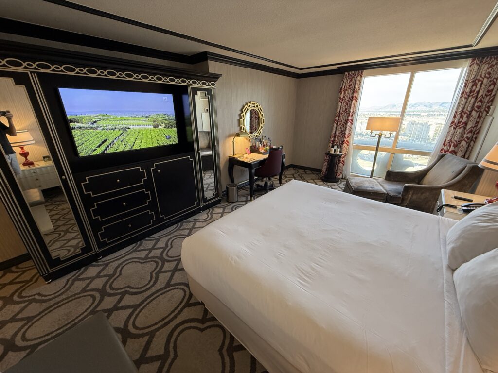 A wide angle shot of the king bed pointd at the TV. 