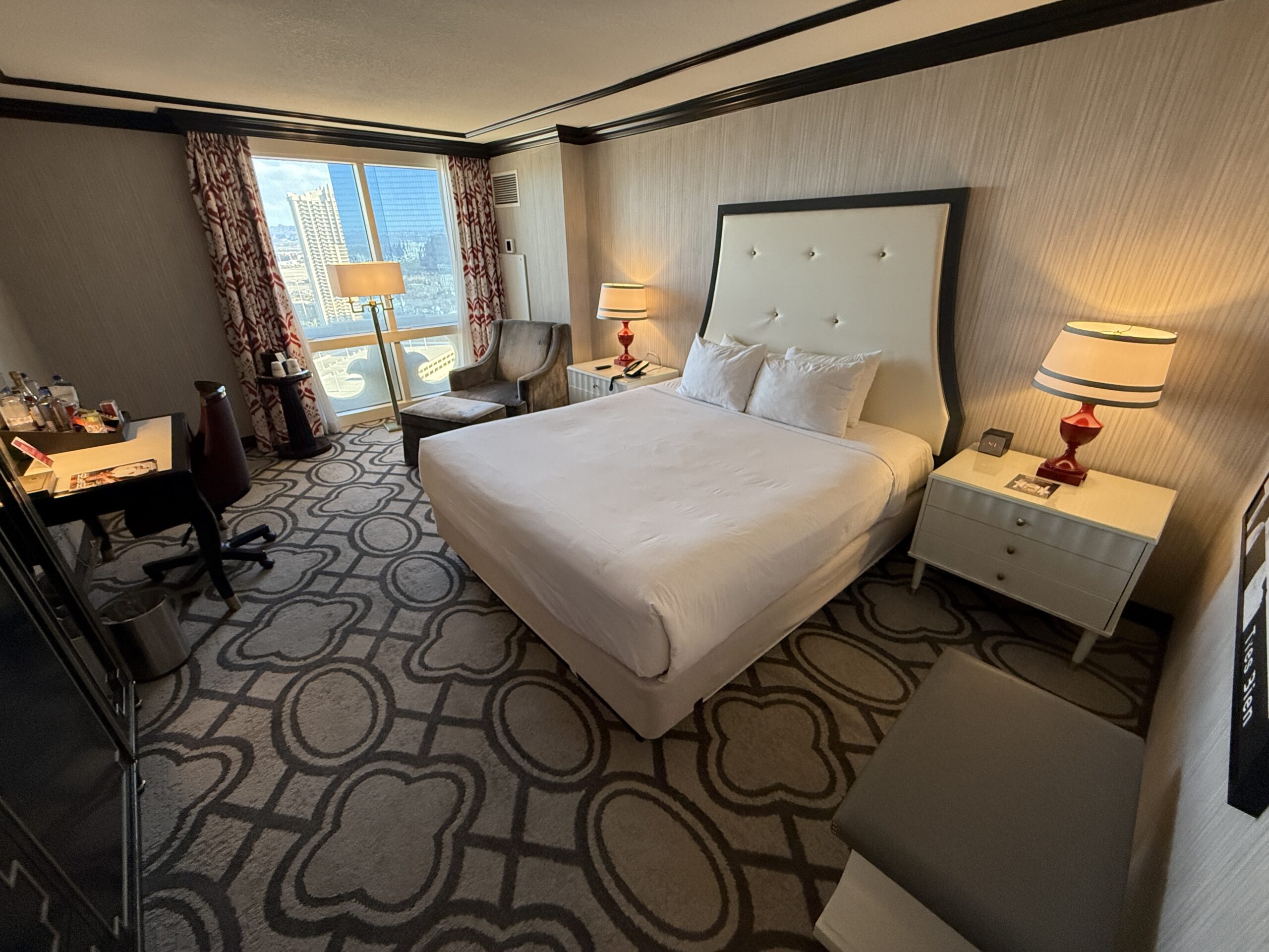 A wide angle of Paris' Bordeaux room with the king bed in the center and window in the background.