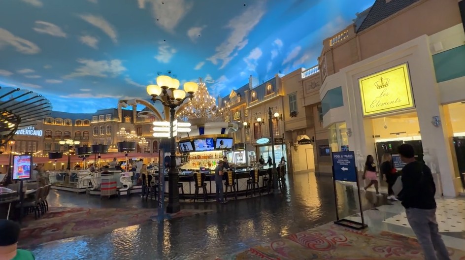 A portion of the caisno floor with blue skies, and fake parisian building facades. 