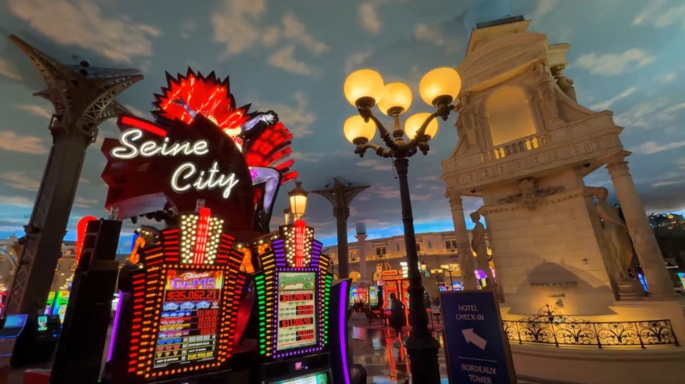 Paris' casino floor with a blue, cloudy sky, street lights, and a bank of slots named "Seine City". 
