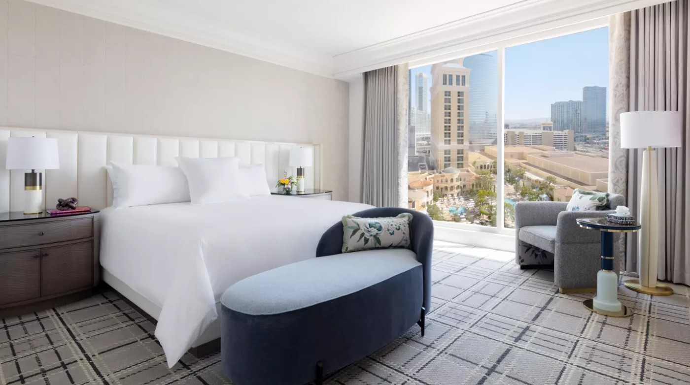 A king bed with a bench at the foot. A window overlooking the Strip is in the background.