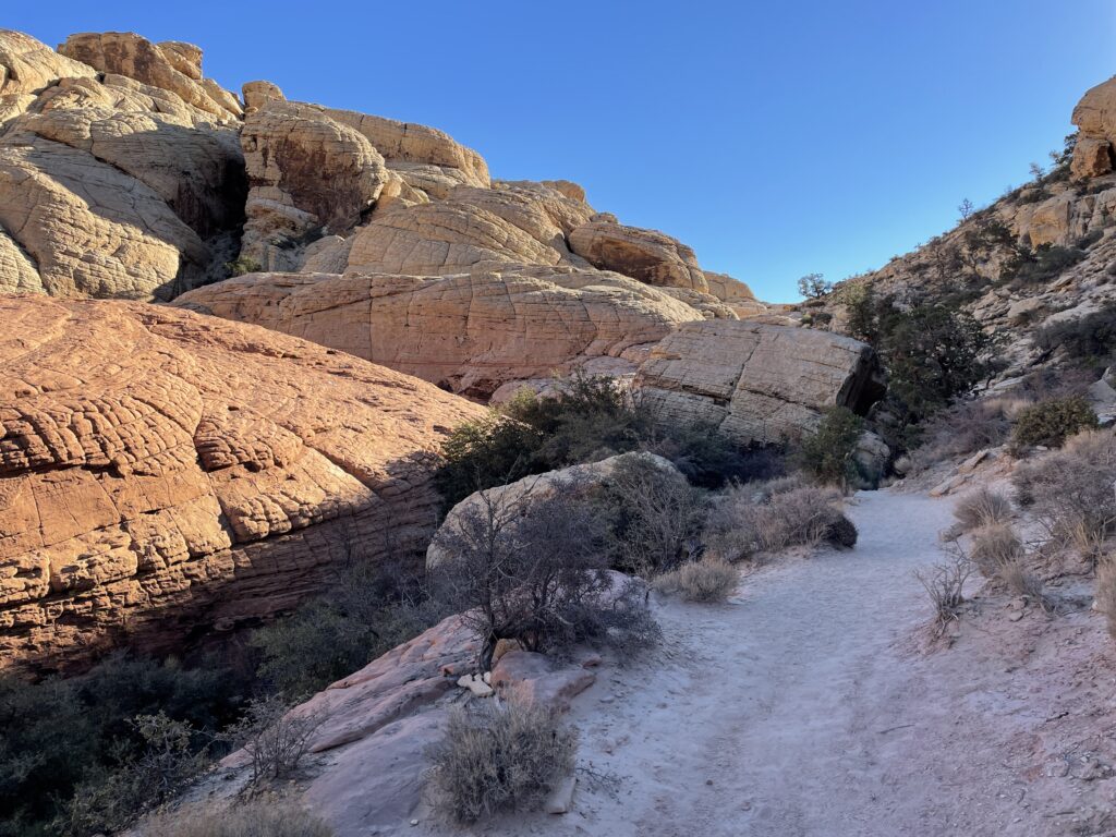 Winding hiking trail with a red rock formation to the left