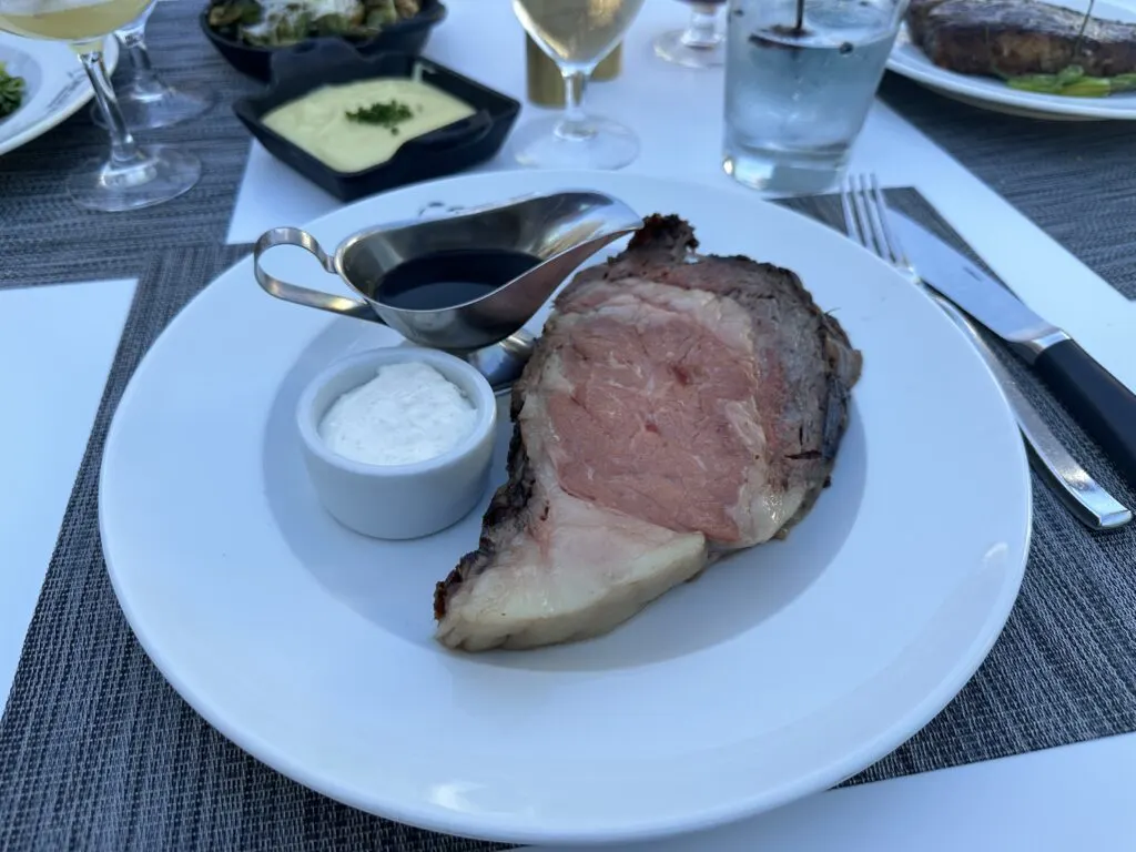 My prime rib from Oscar's Las Vegas on a plate with a small steel container of au jus.