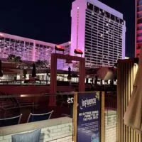 Poolside cabana at night with Flamingo illuminated pink in the background
