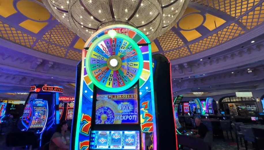 A slot machine in front of a chandelier over Park MGM's casino floor.