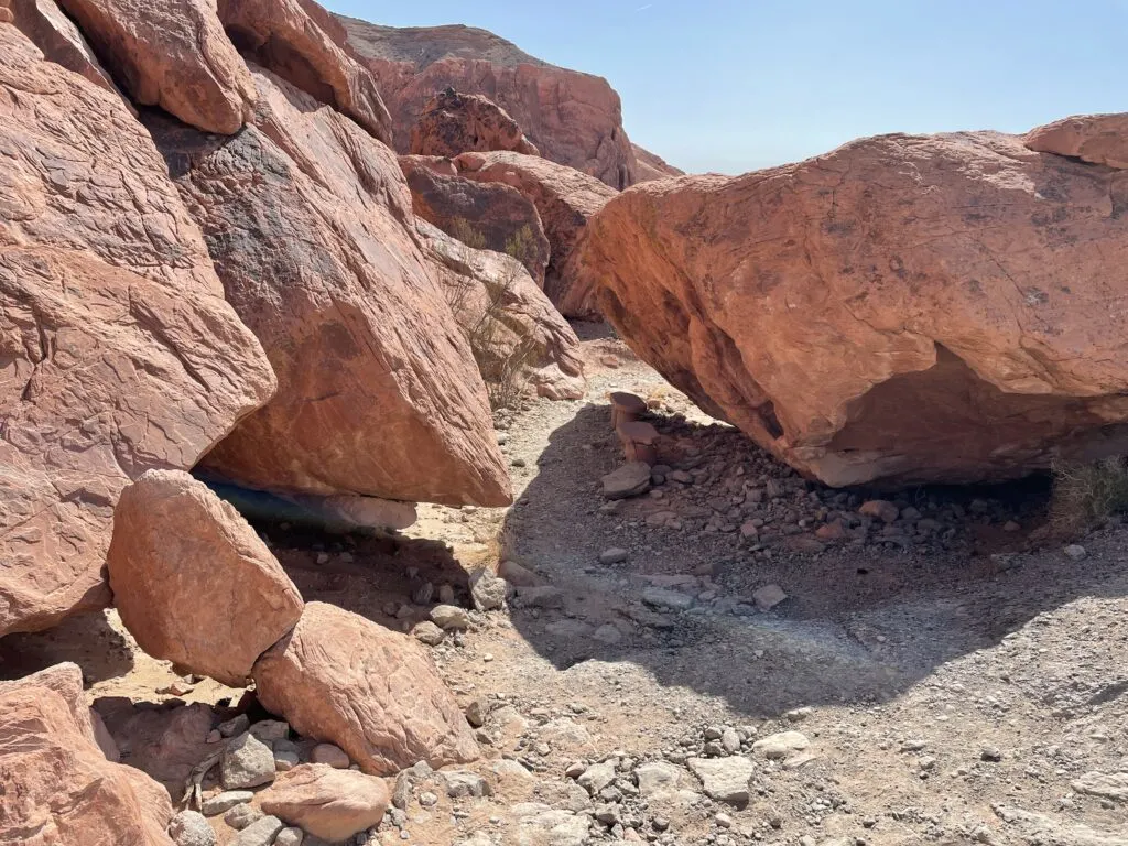 The trail goes downhill and under a large rock to the right