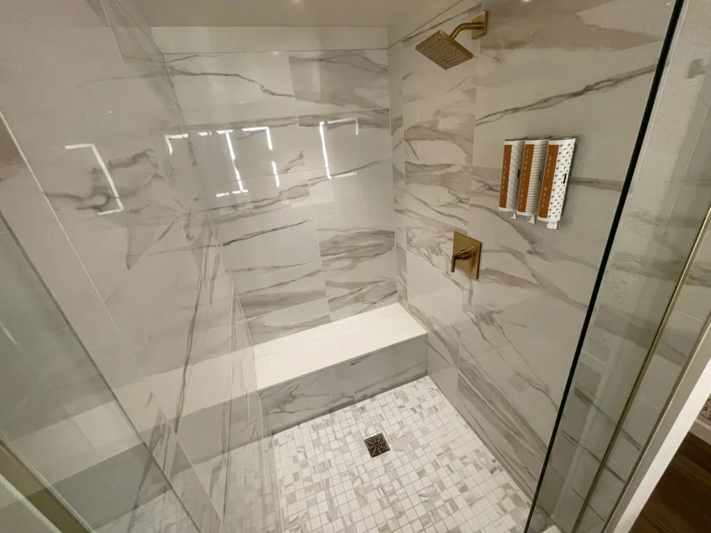 White marble shower with brass fixtures and tile floor