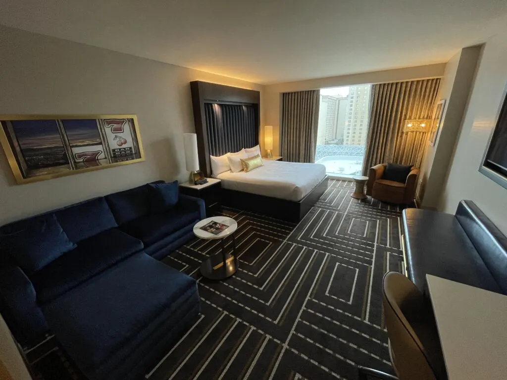 Circa's hotel room with a couch to the left, king bed, and window overlooking Stadium Swim