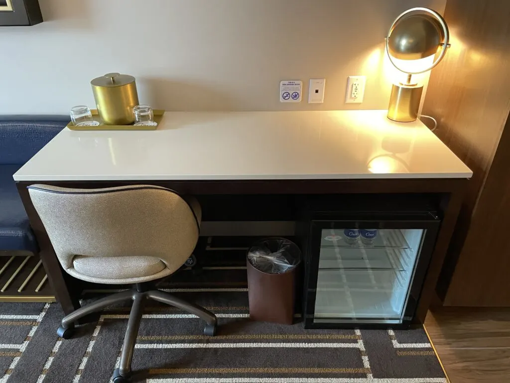 Workdesk with a rolling chair and an empty fridge below