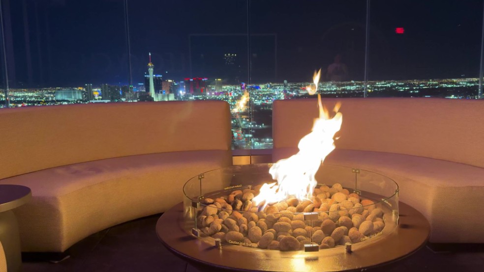 A fire pit surrounded by seating, with a view of the Strip behind it. 