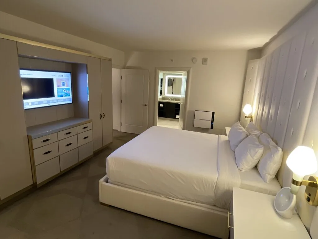 Another angle of the bedroom with the bed, TV and bathroom in the background