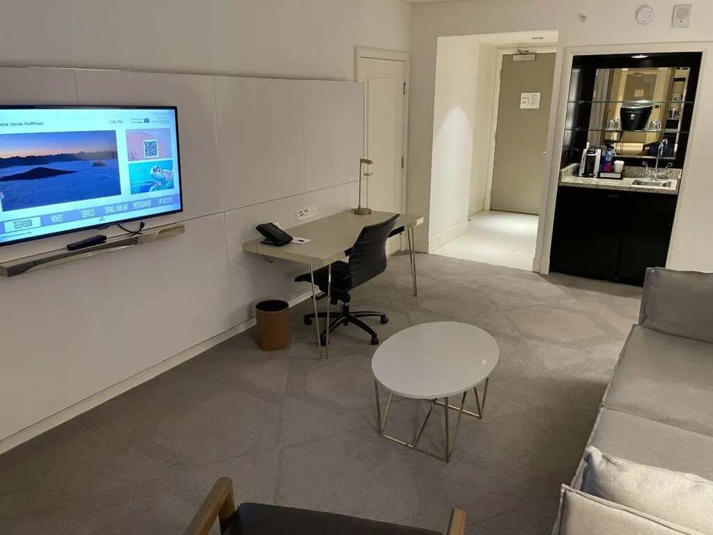 Another angle of the living room that shows the TV, Mini Bar, and workdesk