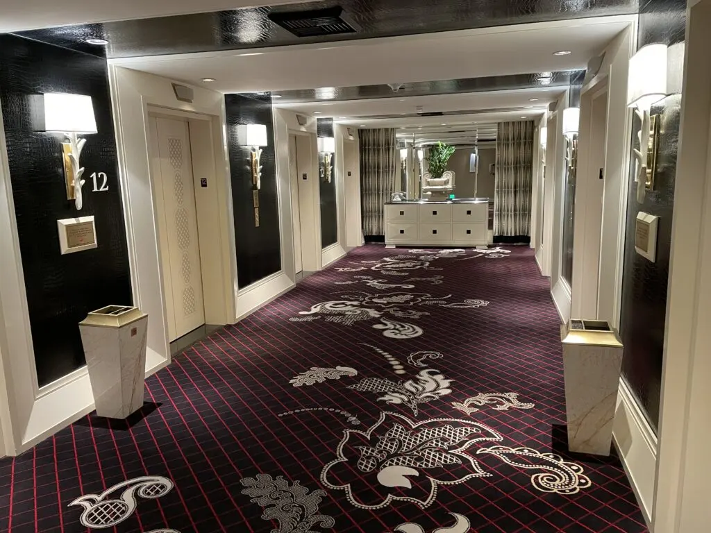 An elevator lobby at Encore with a deep purple floral carpet and 6 elevators