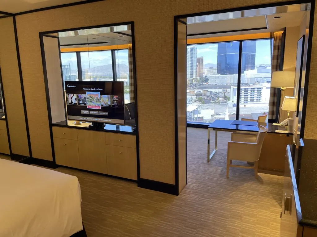 A wall separates the bedroom area, which is in the foreground with the living area in the background. 