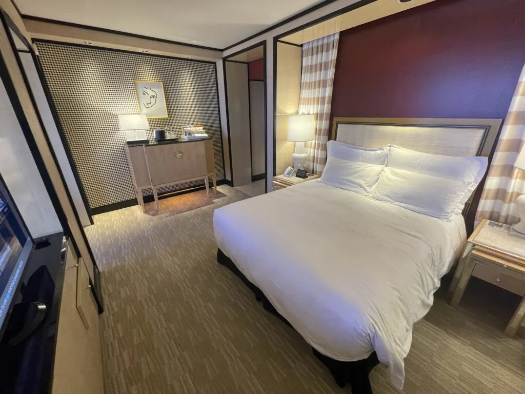 Wide angle shot of the bedroom area with the bed in the foreground and minibar cabinet in the background