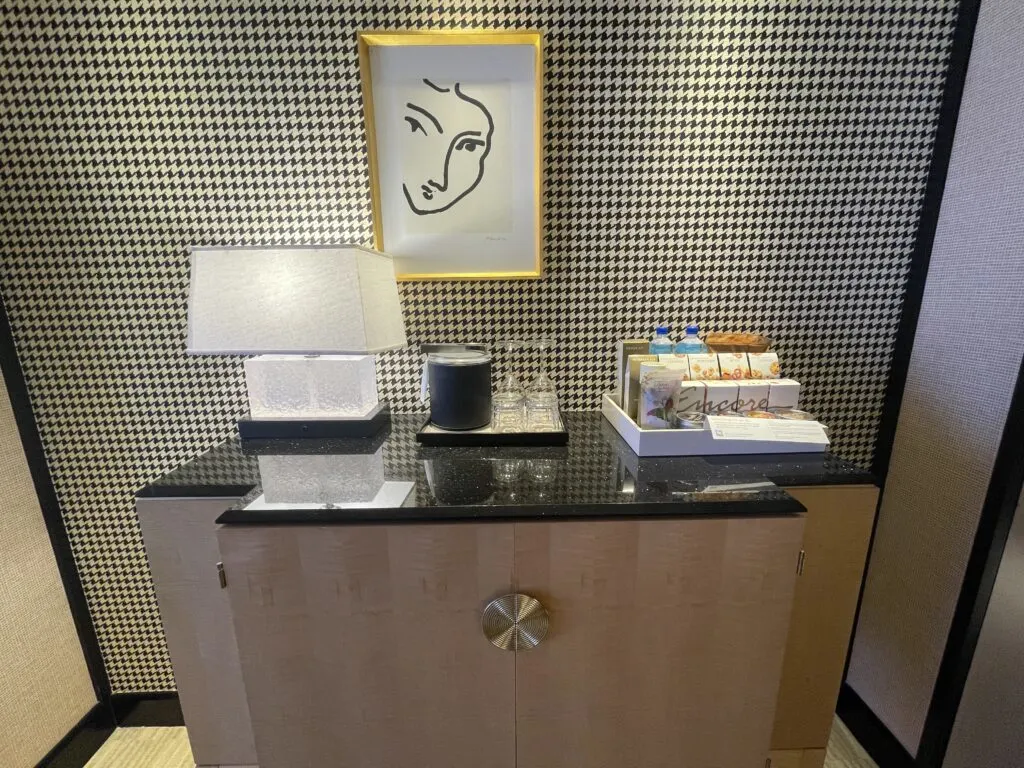 Cabinet with snacks, empty glasses, an ice bucket, and lamp atop it