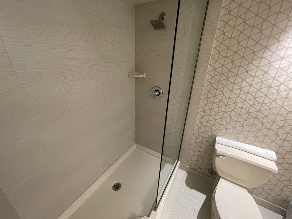 A shower with a glass wall extending 1/3 of the way across the opening