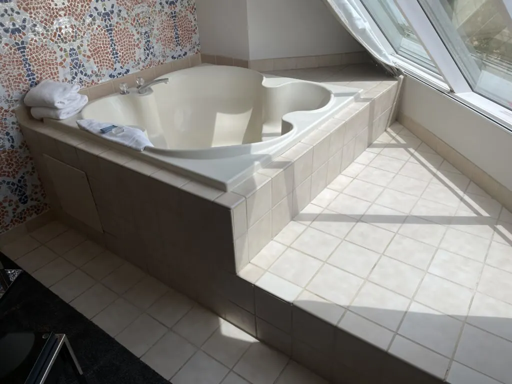 A tile platform under luxor's angled exterior wall that is home to a 2 person bathtub. 