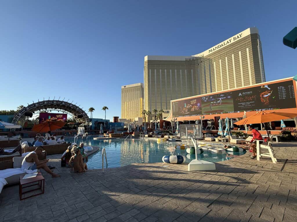 Tailgate Beach Club,, with a pool in the foreground and screens with the game behind it. Mandalay Bay's hotel tower is in the far background.
