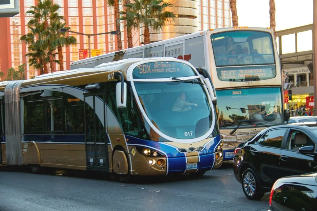 Two busses are next to eachother on the Strip in front of TI