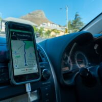 A smartphone is mounted on a car's dashboard providing directions via a maps application