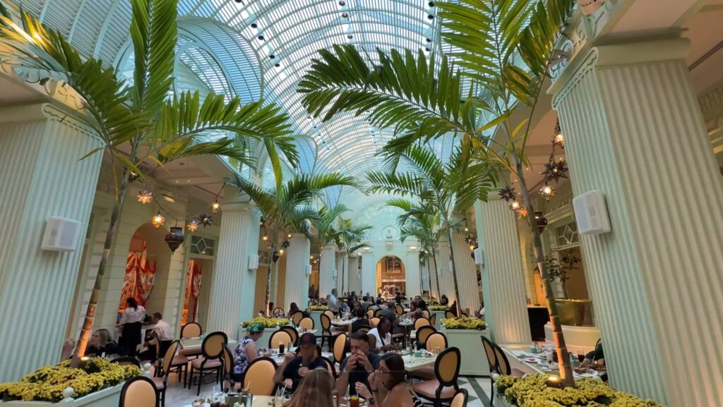 Seating area inside the Buffet at Wynn with glass ceilings and palm trees overhead.